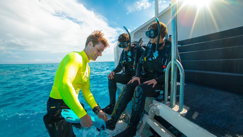 divers having fins fitted on the dive deck